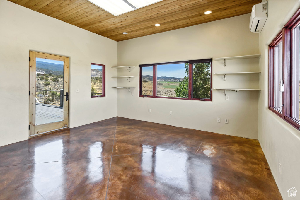 Unfurnished room with a wall unit AC, concrete flooring, wooden ceiling, healthy amount of natural light, and recessed lighting