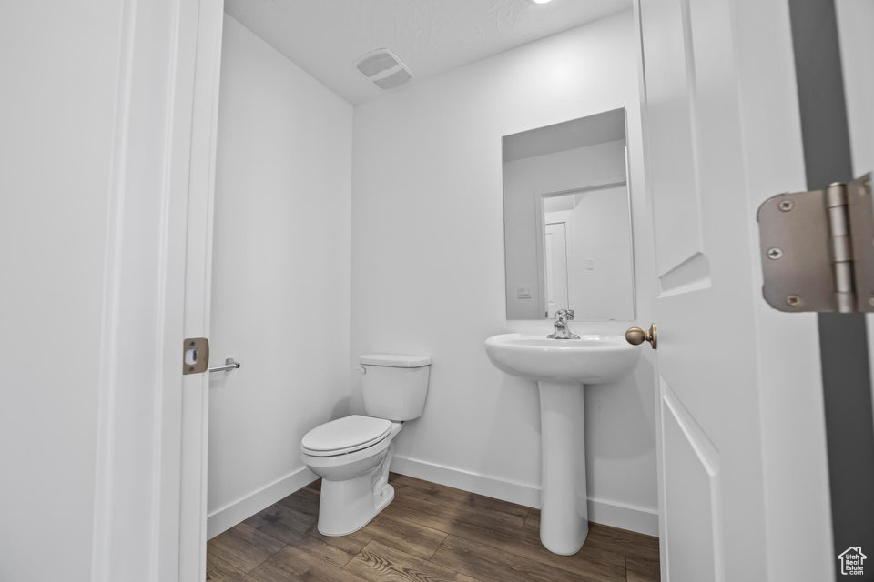 Half bathroom with toilet and wood finished floors