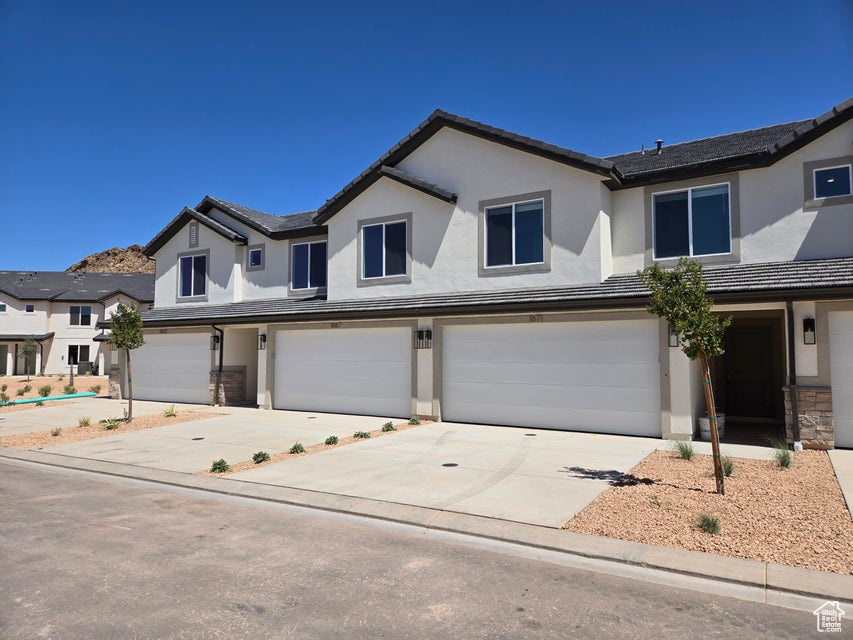 View of front of house featuring an attached garage, stucco siding, driveway, and a tiled roof