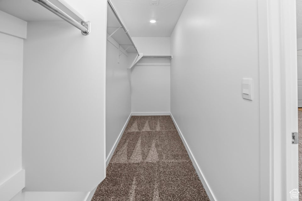 Walk in closet featuring dark carpet