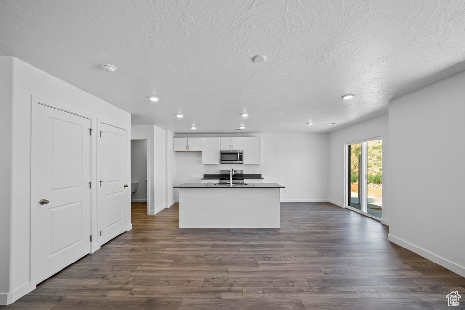Kitchen featuring stainless steel microwave, dark countertops, recessed lighting, white cabinets, and dark wood-style floors
