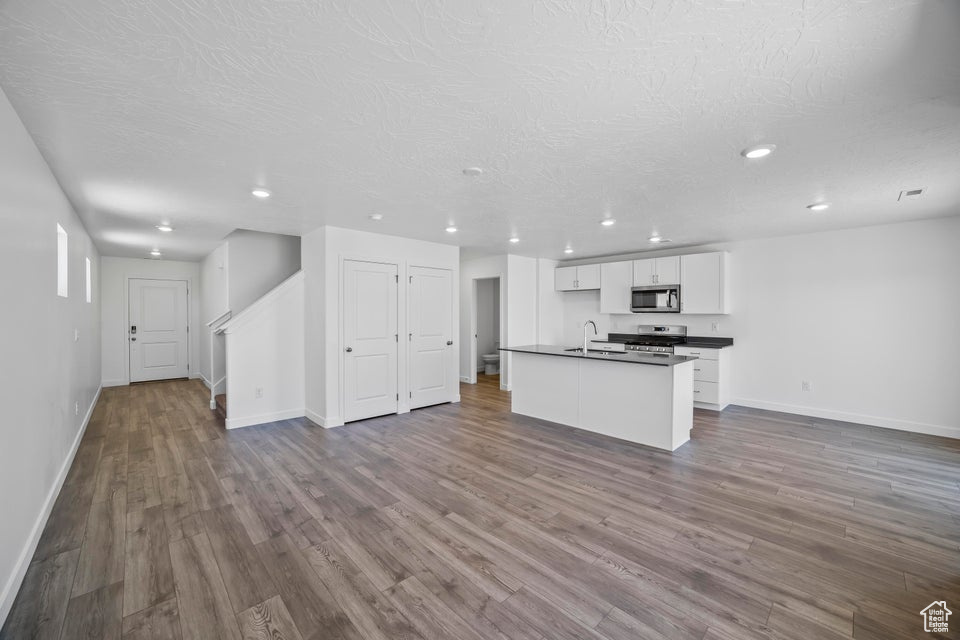 Unfurnished living room with dark wood-style flooring, recessed lighting, and a textured ceiling