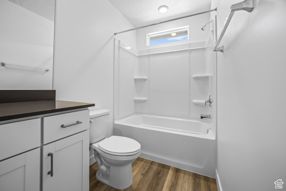 Bathroom featuring shower / tub combination, wood finished floors, vanity, and a textured ceiling