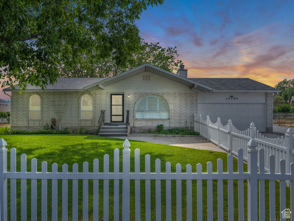 Ranch-style house featuring a fenced front yard, a garage, and brick siding