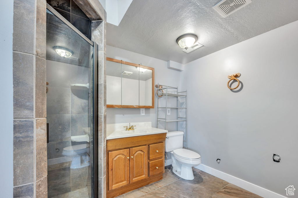 Full bath with vanity, a stall shower, and a textured ceiling