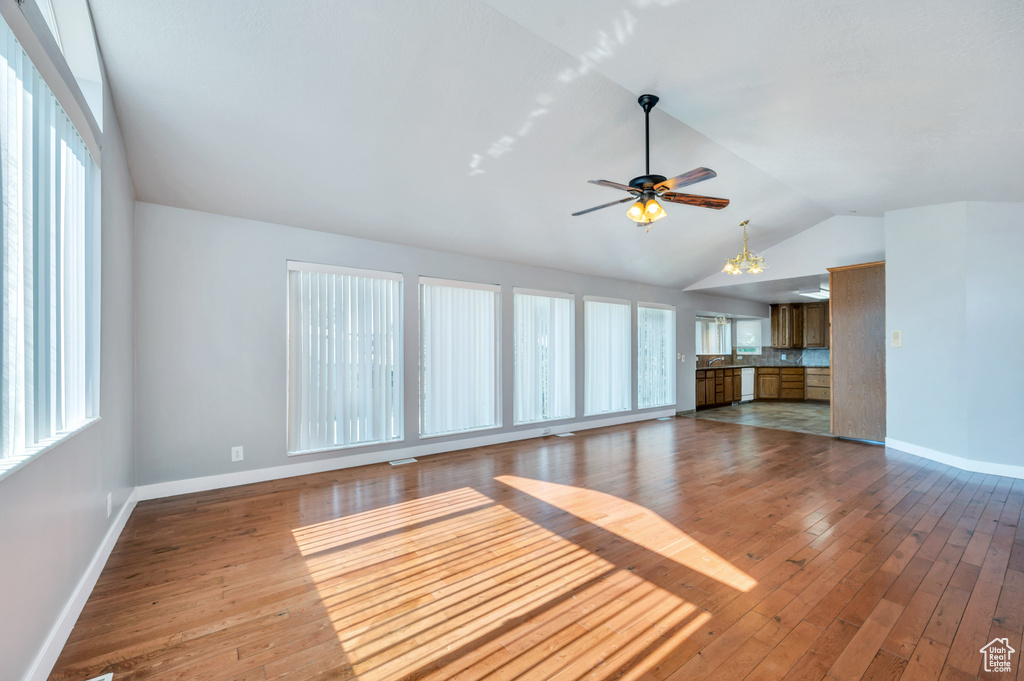 Unfurnished living room featuring lofted ceiling, healthy amount of natural light, hardwood / wood-style floors, and a ceiling fan