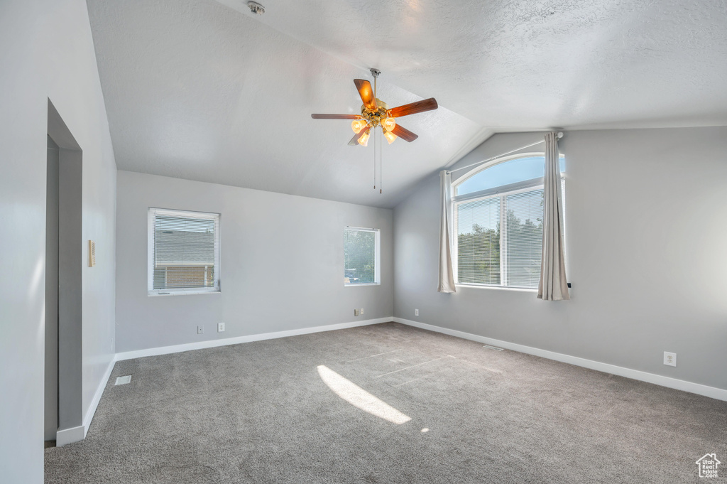 Spare room with vaulted ceiling, carpet flooring, and ceiling fan