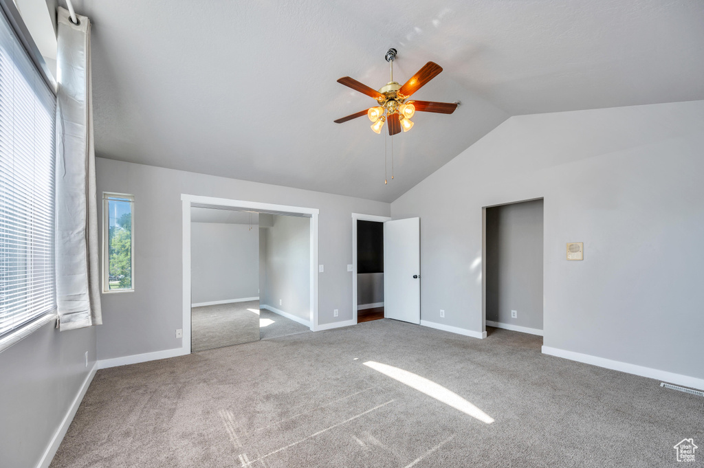Unfurnished bedroom featuring vaulted ceiling, carpet floors, ceiling fan, and a closet