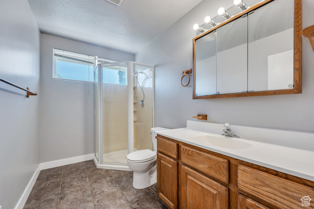 Full bath featuring vanity, a stall shower, and a textured ceiling