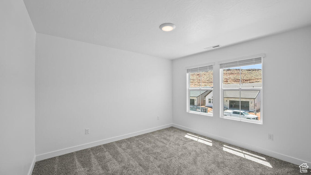 Carpeted spare room featuring baseboards