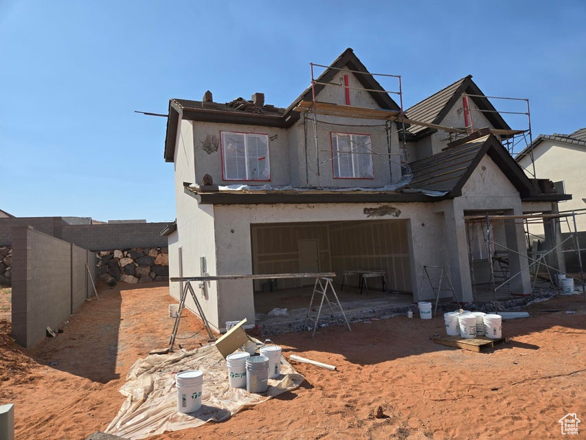 Rear view of property featuring an attached garage and stucco siding
