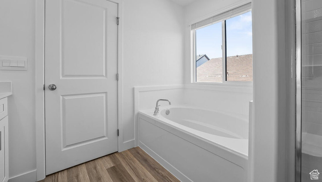 Full bath featuring a garden tub, wood finished floors, and vanity