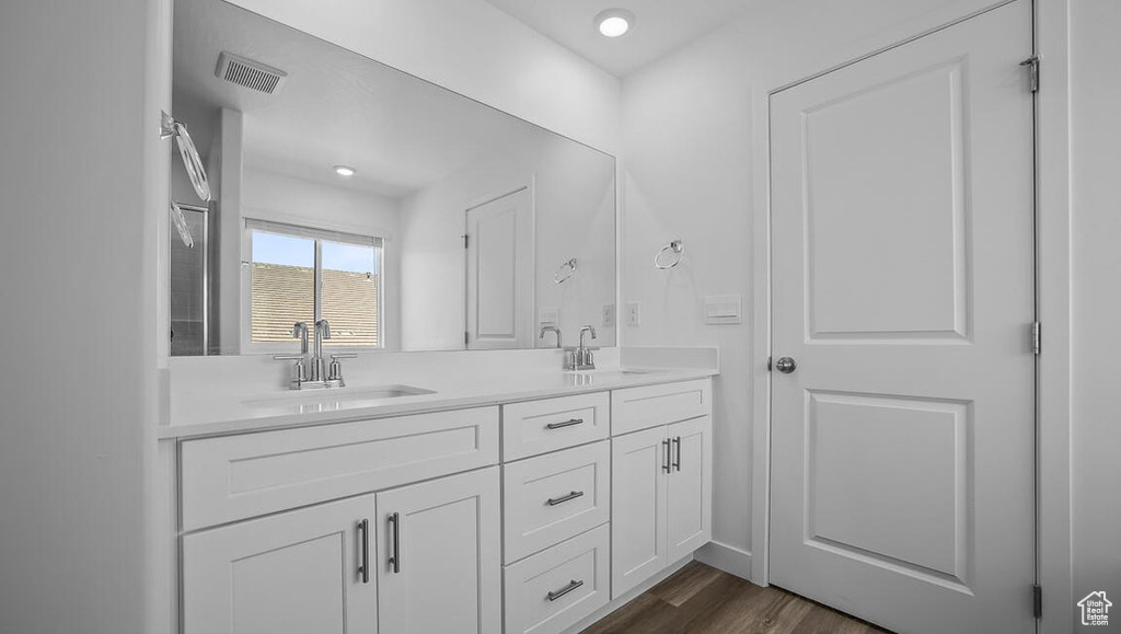 Bathroom with double vanity, wood finished floors, and recessed lighting