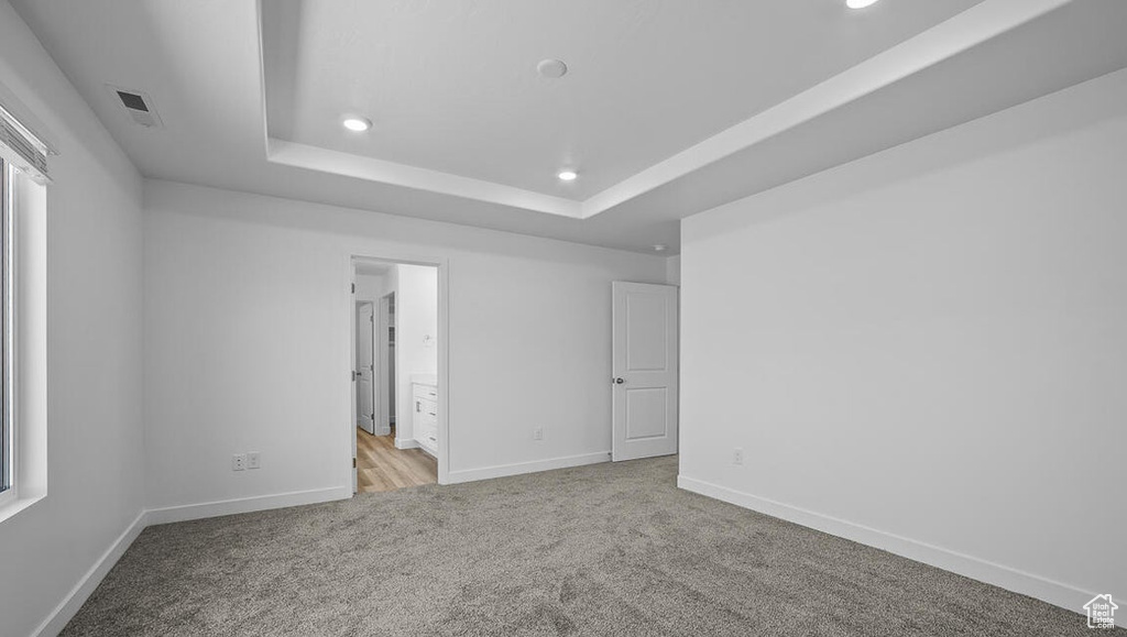 Unfurnished bedroom with carpet flooring, recessed lighting, a raised ceiling, and ensuite bathroom