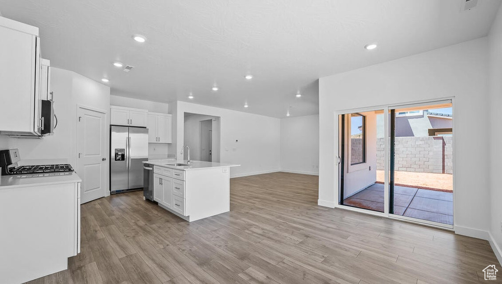 Kitchen featuring stainless steel appliances, light wood-style flooring, recessed lighting, open floor plan, and white cabinets