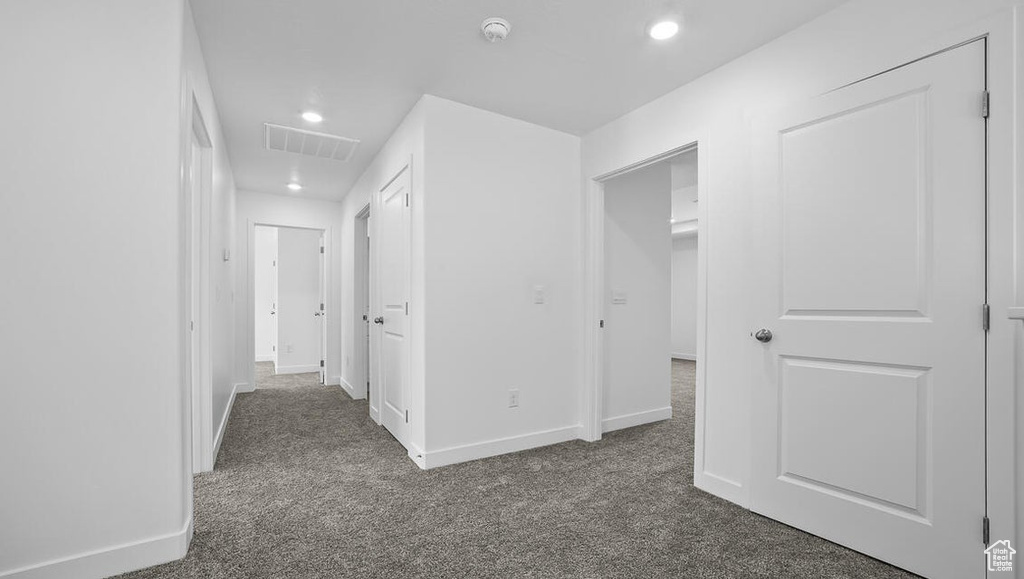 Corridor featuring dark colored carpet and recessed lighting
