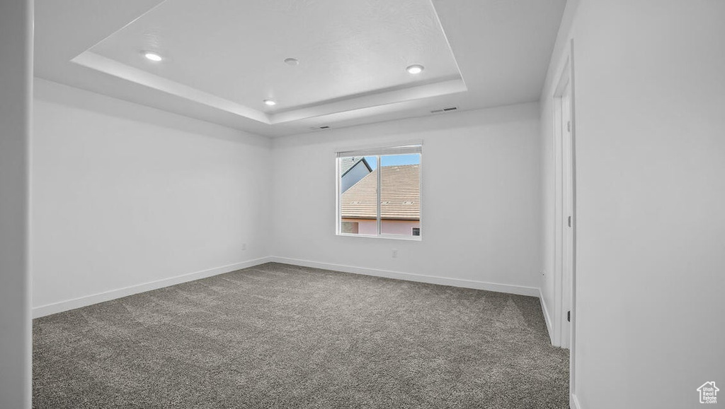 Carpeted empty room featuring a raised ceiling and recessed lighting