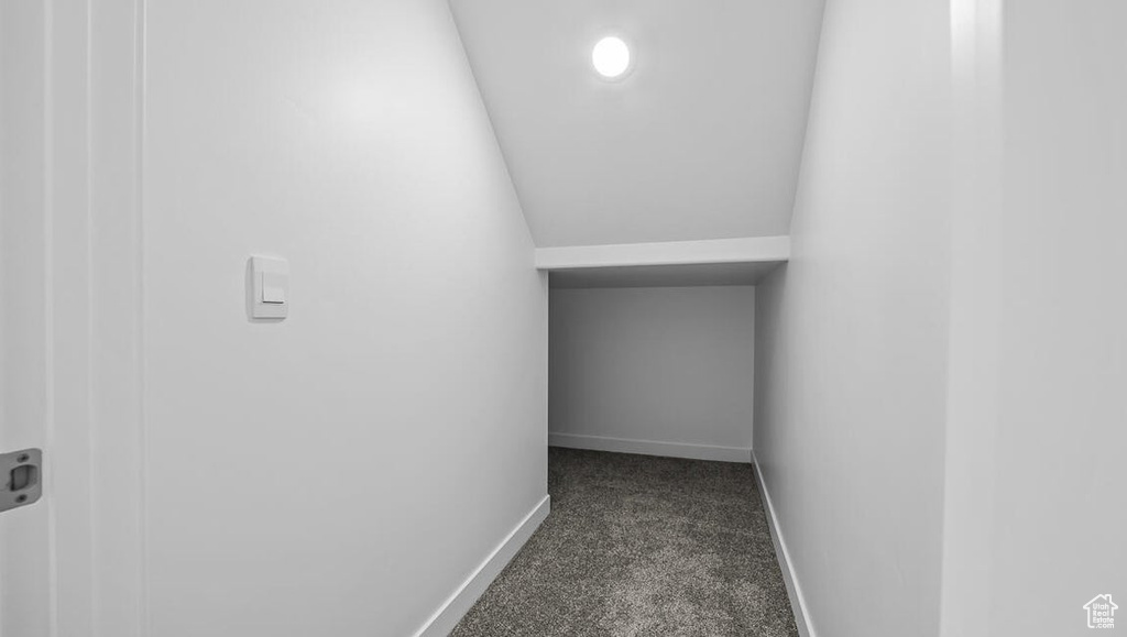Hall featuring dark carpet and baseboards
