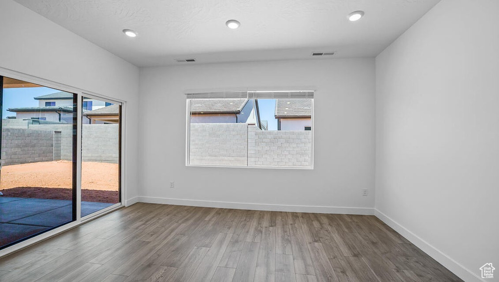 Empty room featuring healthy amount of natural light, wood finished floors, and recessed lighting