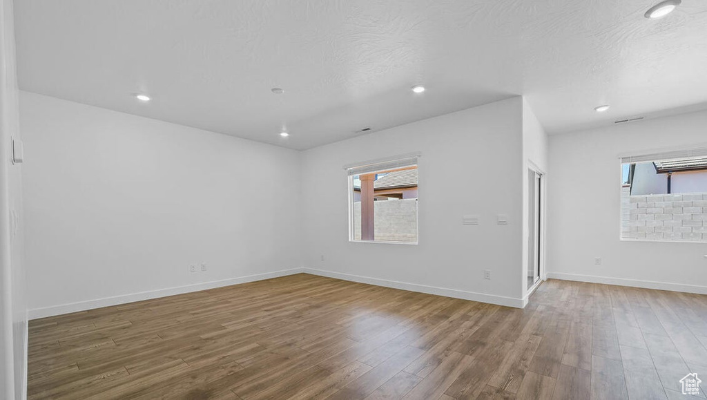 Spare room with wood finished floors, healthy amount of natural light, and recessed lighting