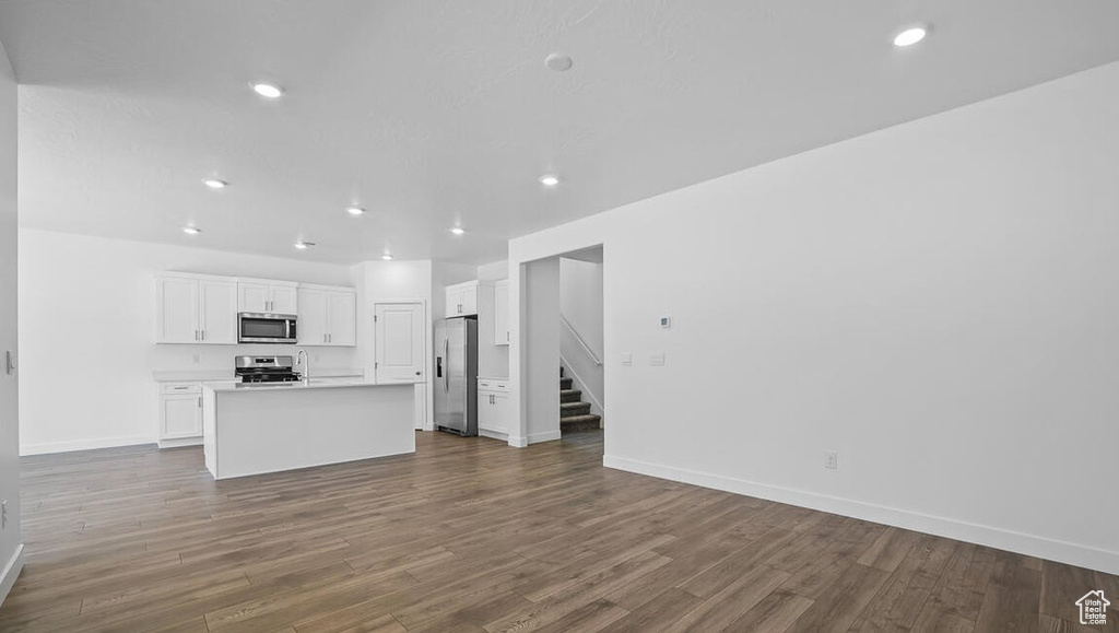 Unfurnished living room featuring stairway, dark wood-type flooring, and recessed lighting
