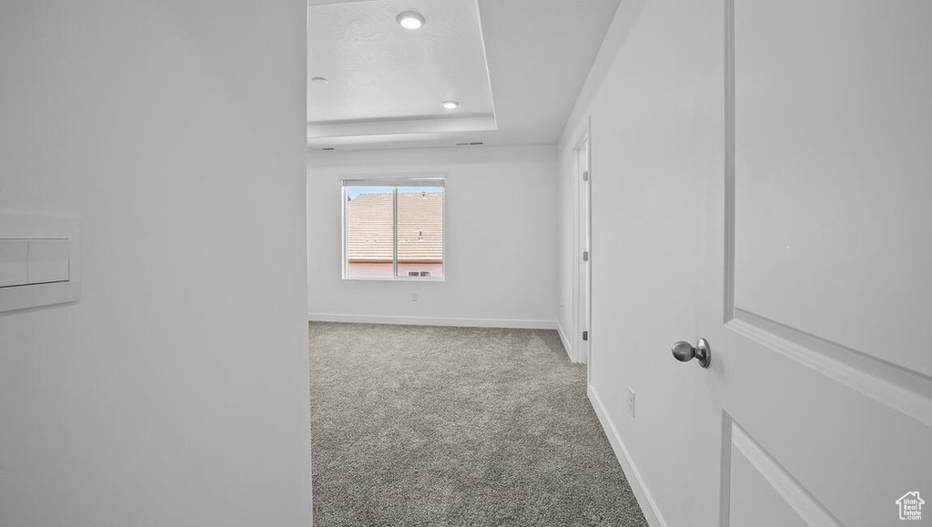 Carpeted spare room featuring a tray ceiling and recessed lighting