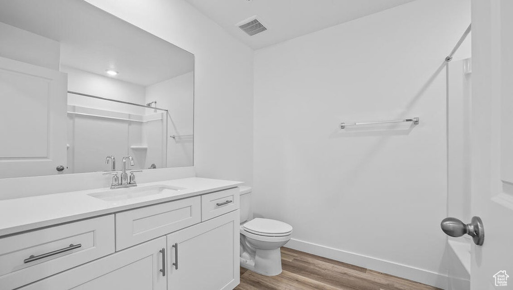 Bathroom featuring wood finished floors, a shower, and vanity