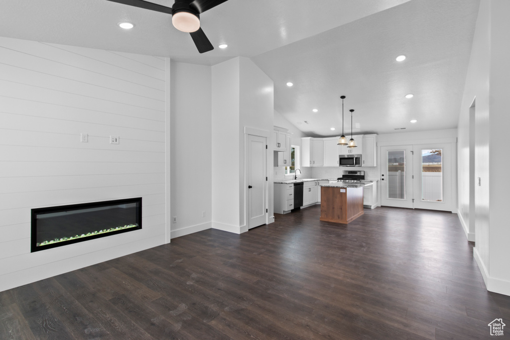 Unfurnished living room with a large fireplace, a ceiling fan, recessed lighting, dark wood finished floors, and high vaulted ceiling