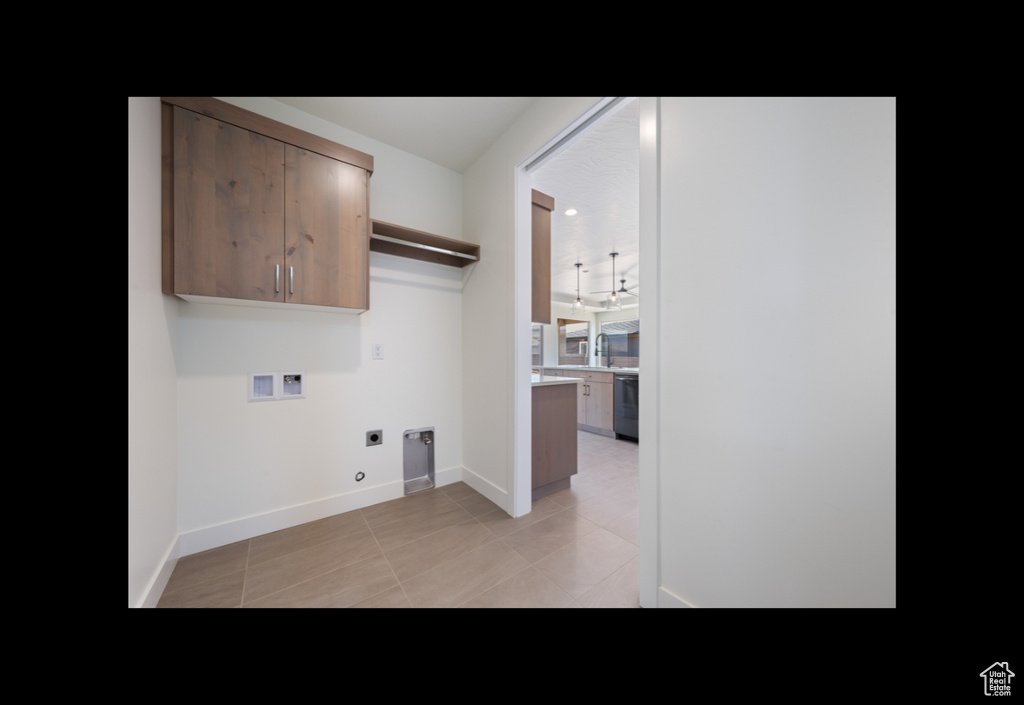 Laundry room featuring electric dryer hookup, hookup for a washing machine, light tile patterned floors, and cabinet space