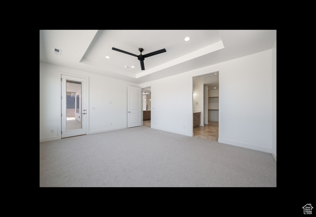 Unfurnished bedroom with a raised ceiling, light carpet, ensuite bath, and recessed lighting