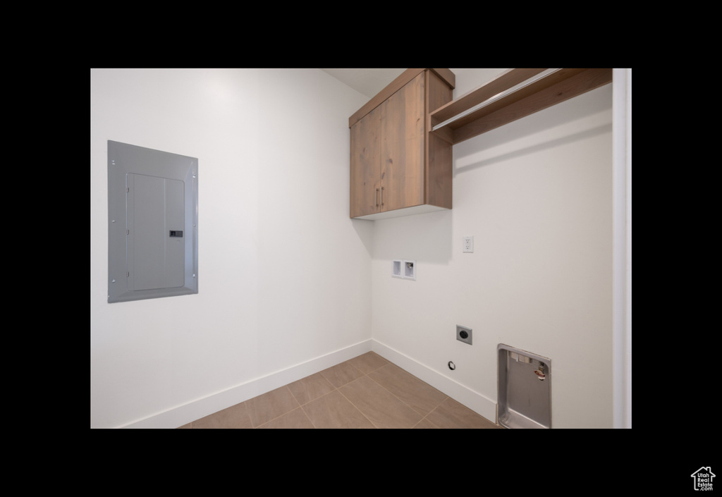 Washroom with electric panel, electric dryer hookup, hookup for a washing machine, cabinet space, and light tile patterned floors