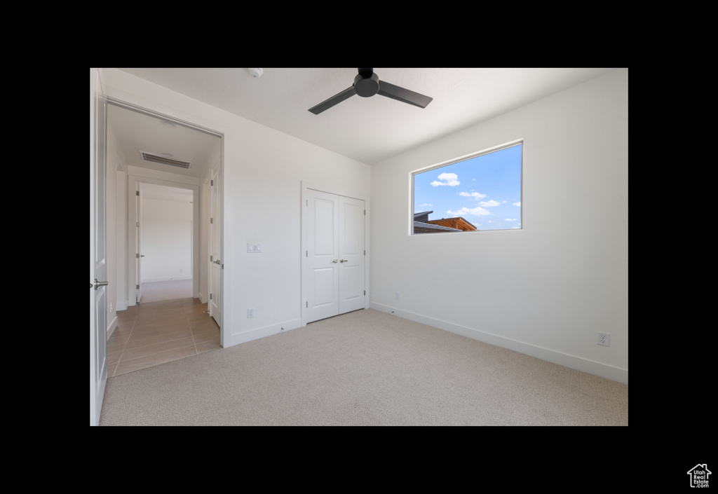 Unfurnished bedroom with light carpet, a ceiling fan, and a closet