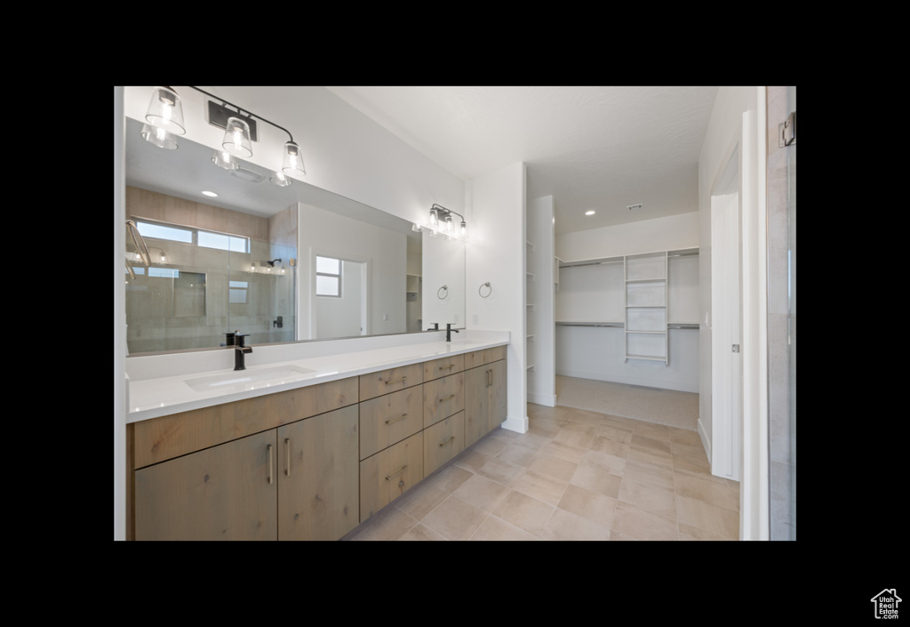 Full bathroom with a shower stall, double vanity, a spacious closet, and tile patterned flooring