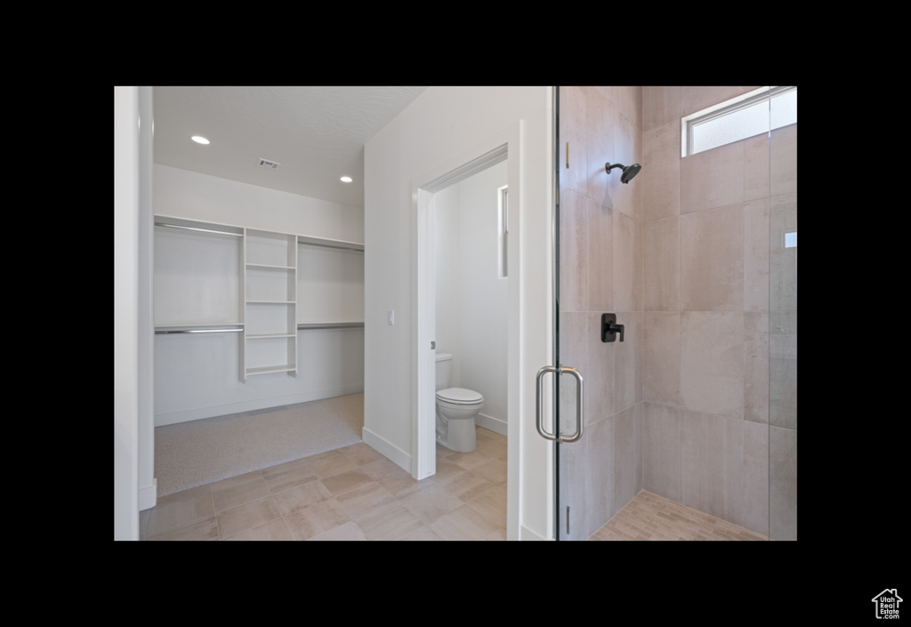 Full bath with a shower stall, a spacious closet, and recessed lighting