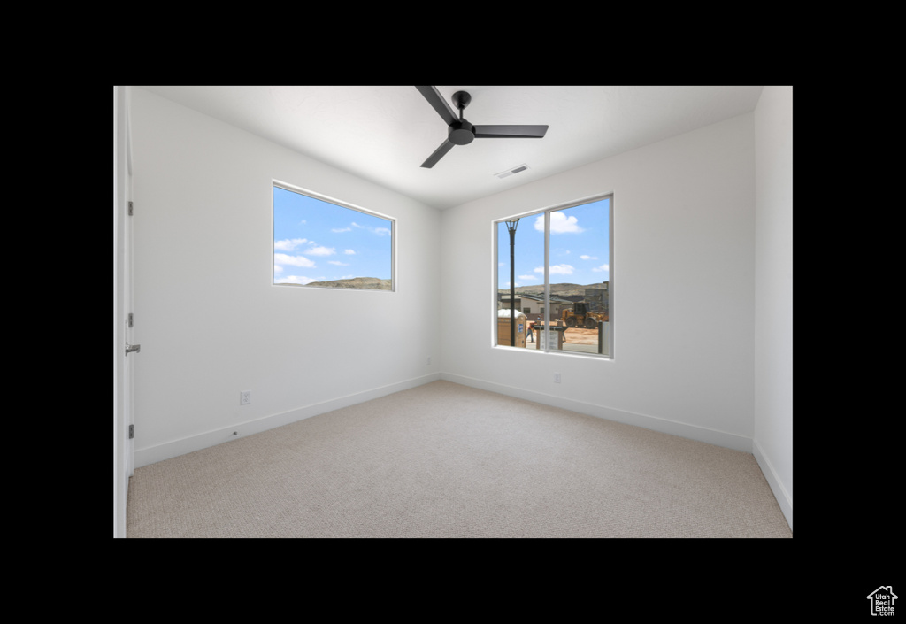 Carpeted empty room featuring a ceiling fan and baseboards