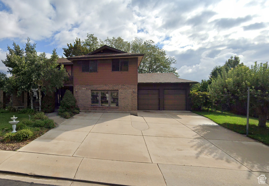 View of front of house featuring a garage, brick siding, and driveway
