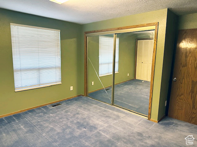 Unfurnished bedroom with carpet flooring, a closet, and a textured ceiling