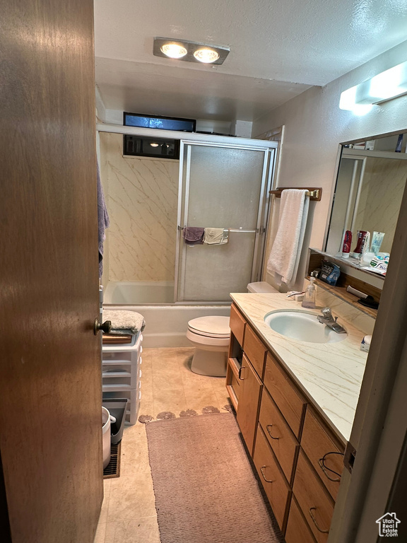 Bathroom with vanity, shower / bath combination with glass door, and a textured ceiling