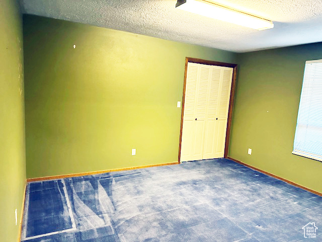 Unfurnished bedroom with a textured ceiling, a closet, and carpet floors