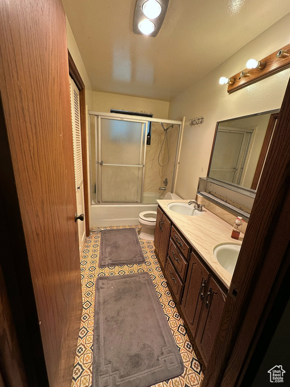 Full bath with shower / bath combination with glass door, double vanity, and tile patterned flooring