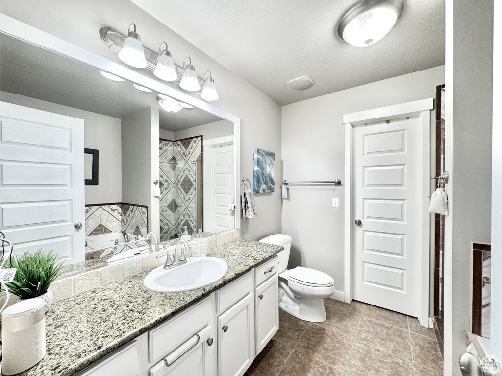 Bathroom featuring vanity, tile patterned floors, a bath, a tile shower, and a textured ceiling