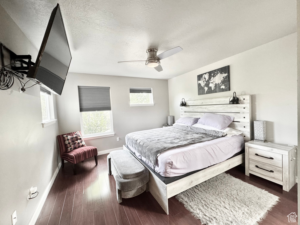 Bedroom featuring a textured ceiling, dark wood finished floors, and a ceiling fan