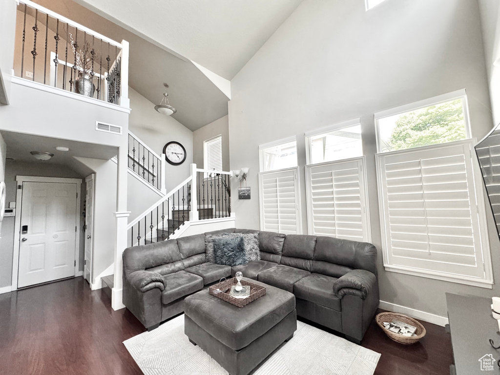 Living room with high vaulted ceiling, stairway, and dark wood-type flooring