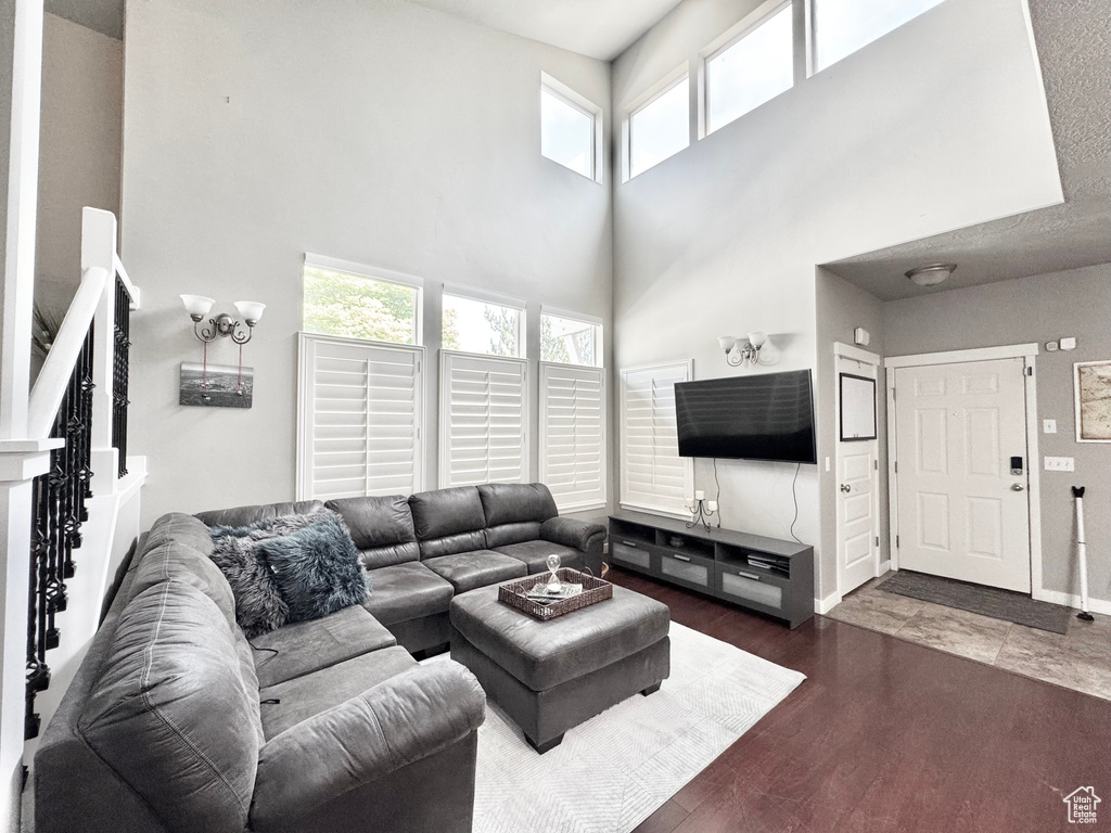 Living area featuring a towering ceiling and dark wood-style floors