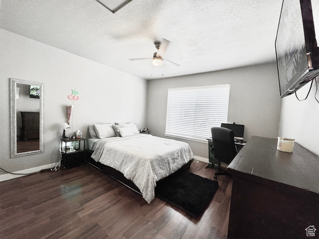 Bedroom featuring dark wood finished floors, a desk, a ceiling fan, and a textured ceiling