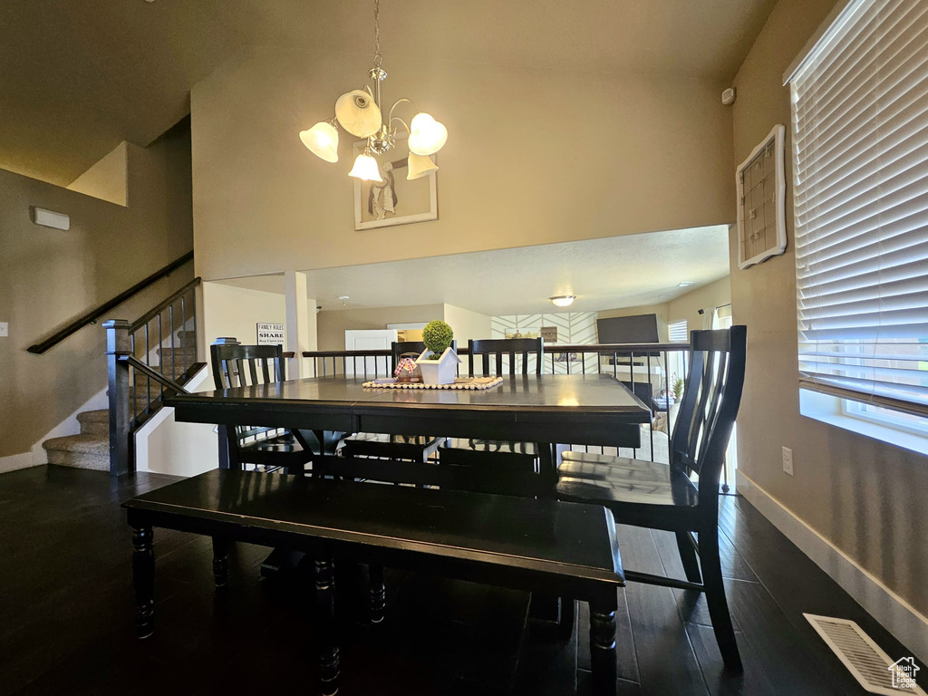 Dining area featuring a chandelier, a high ceiling, wood finished floors, and stairway