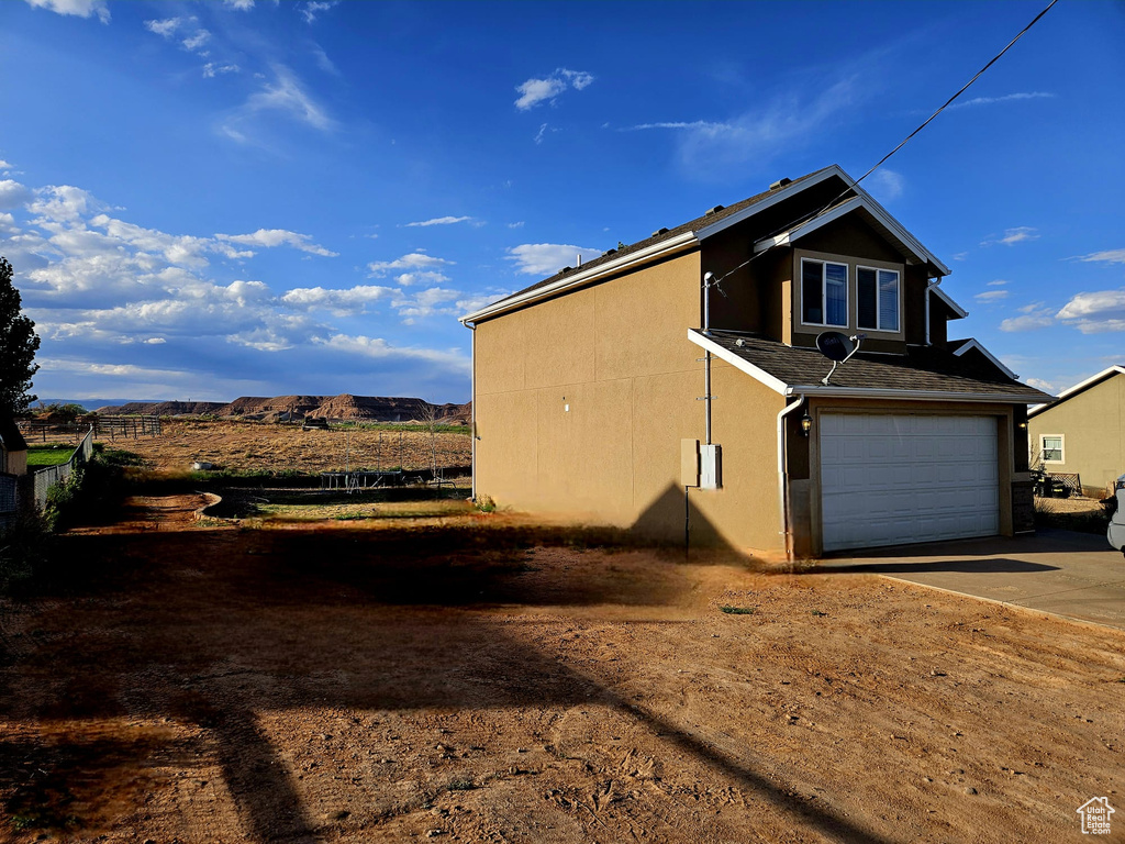 View of side of property with driveway, an attached garage, and stucco siding