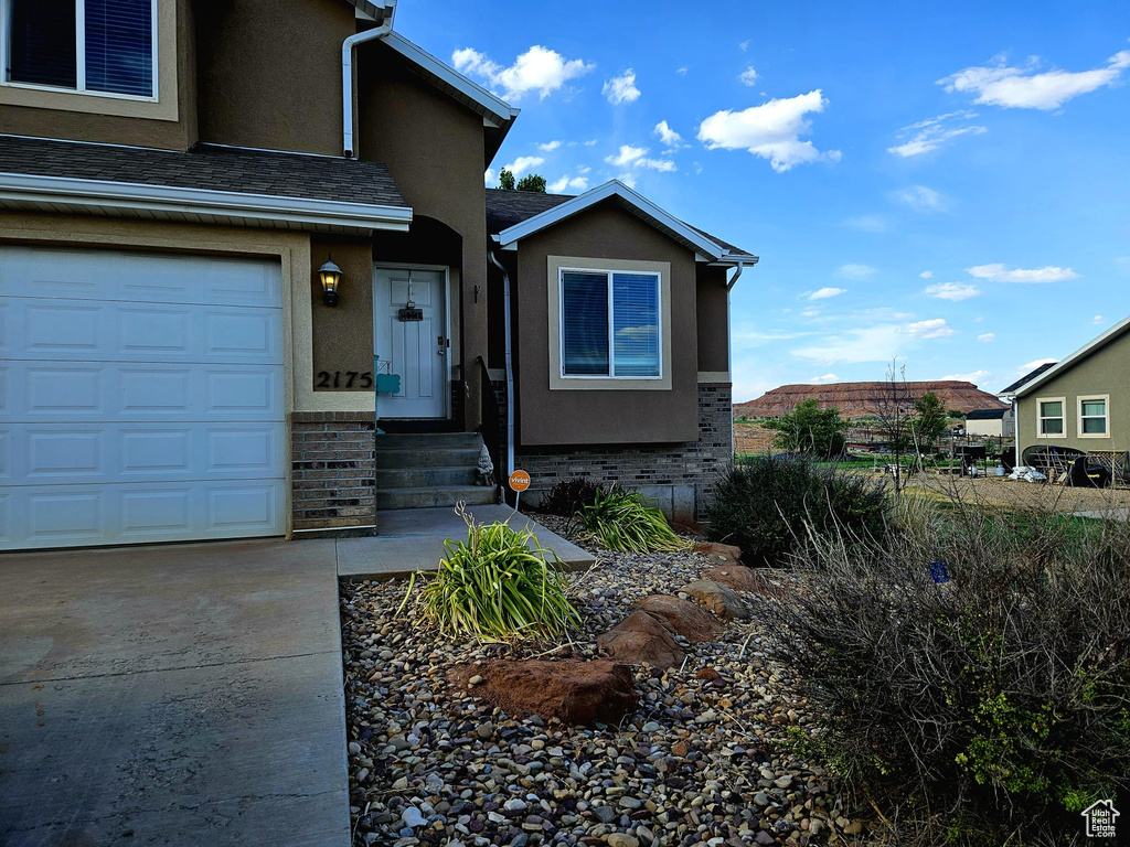View of front facade with brick siding, stucco siding, and driveway
