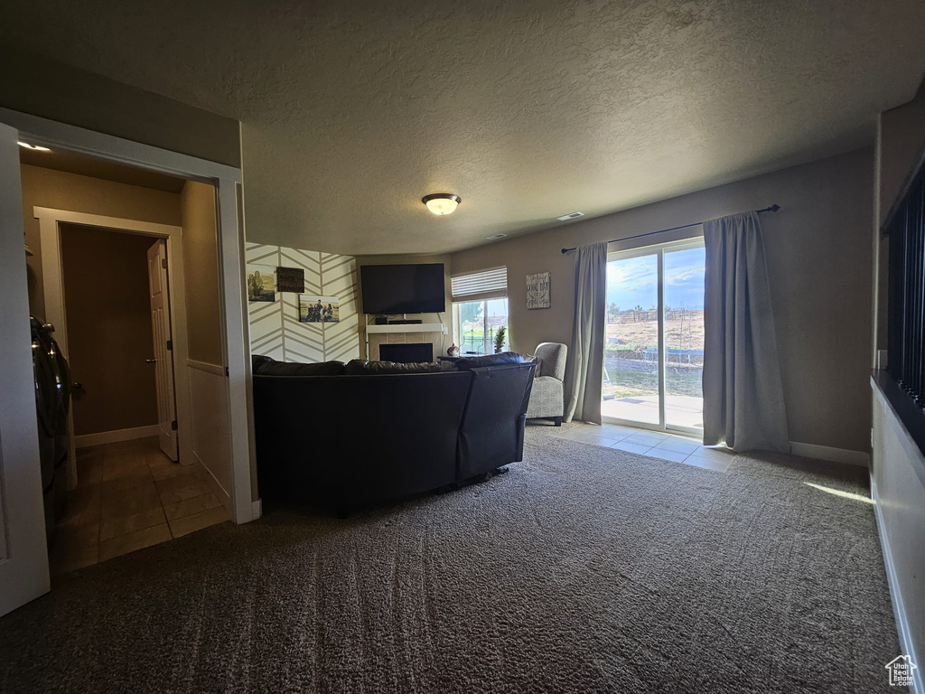 Living area with tile patterned flooring, carpet flooring, a textured ceiling, and a tiled fireplace