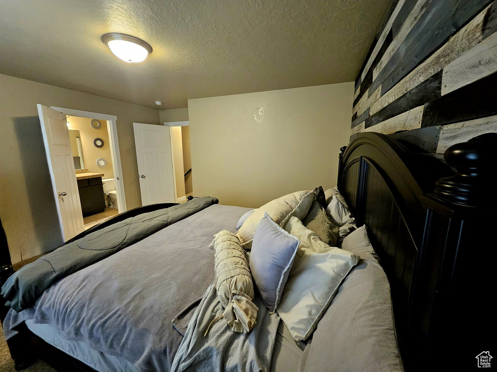 Bedroom with a textured ceiling and ensuite bathroom